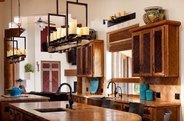 kitchen with brown cabinetry, decorative backsplash, ceiling fan, and a sink