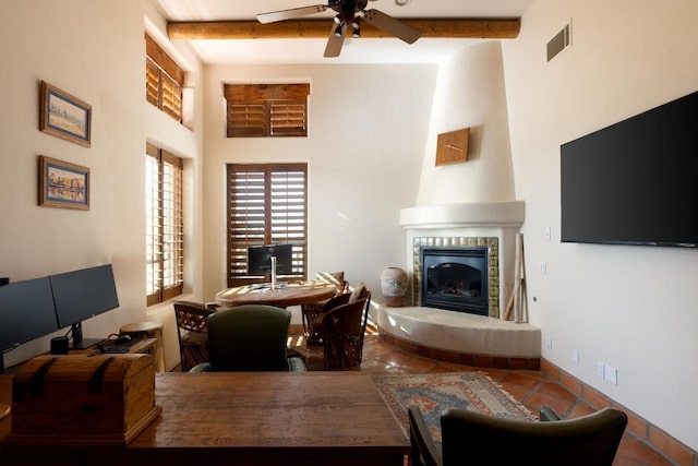 tiled living room featuring baseboards, visible vents, ceiling fan, a tile fireplace, and beamed ceiling