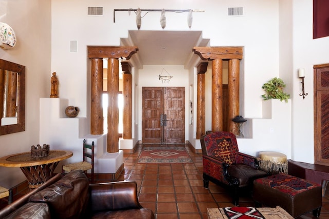 foyer entrance with tile patterned floors, visible vents, and ornate columns