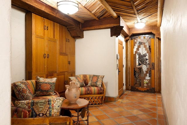 living area with baseboards, beam ceiling, wooden ceiling, and light tile patterned flooring