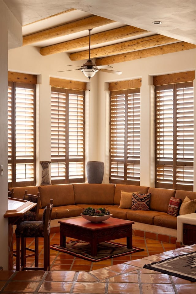 living area featuring beamed ceiling and a ceiling fan