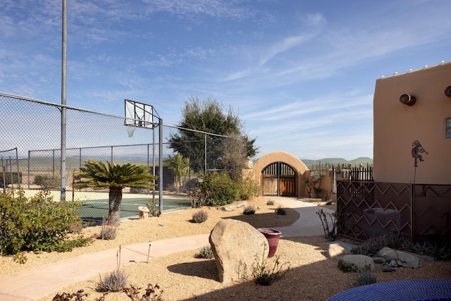 view of basketball court featuring community basketball court, a gate, and fence