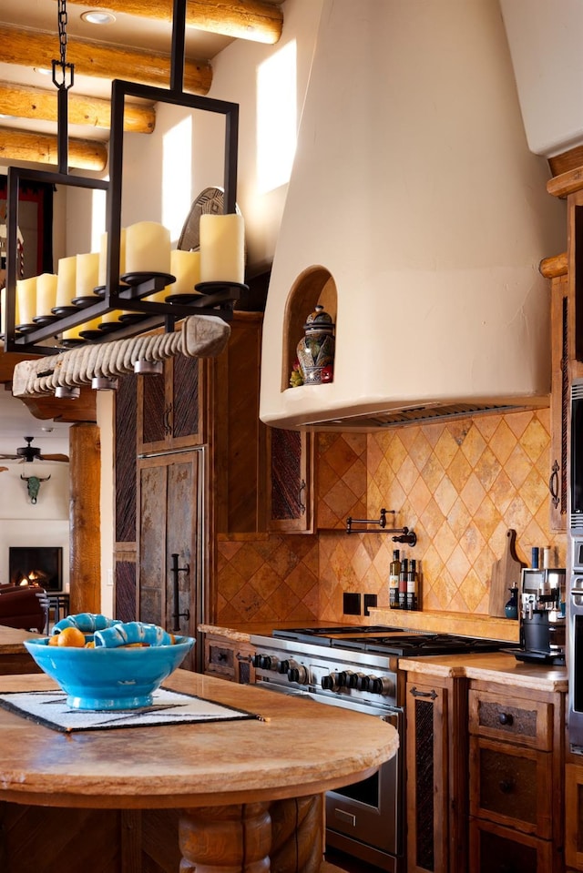 kitchen with open floor plan, decorative backsplash, a lit fireplace, and range with two ovens