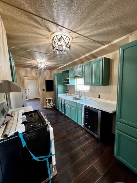 kitchen featuring black gas stove, wood finish floors, beverage cooler, light countertops, and a sink