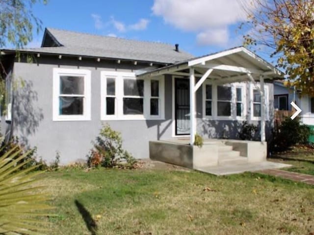 rear view of house featuring stucco siding and a yard