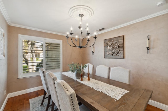 dining room with an inviting chandelier, crown molding, wood finished floors, and baseboards