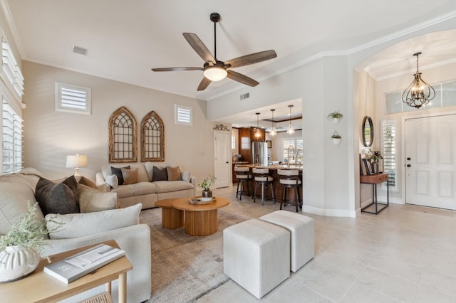 living room with visible vents, ceiling fan with notable chandelier, crown molding, and baseboards