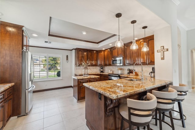 kitchen featuring a sink, a peninsula, tasteful backsplash, and stainless steel appliances