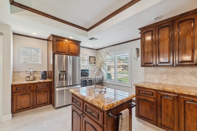 kitchen with light stone counters, stainless steel fridge, backsplash, and ornamental molding