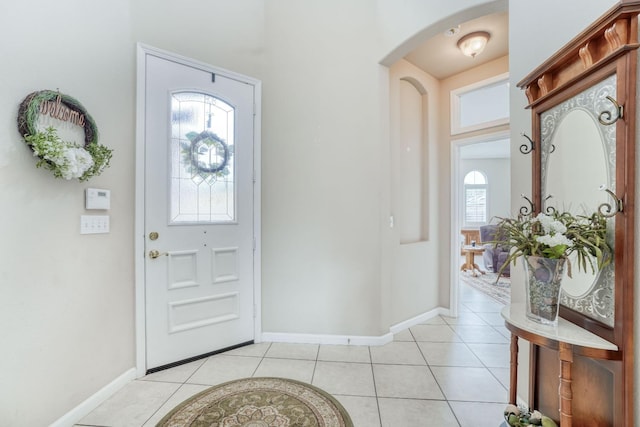 entrance foyer with light tile patterned floors, arched walkways, and baseboards