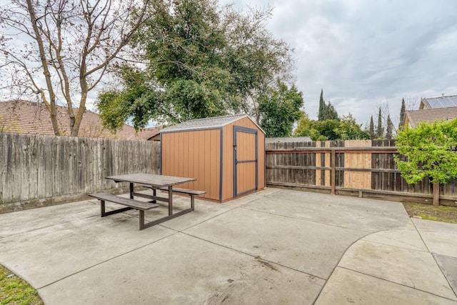 view of patio / terrace with an outdoor structure, a fenced backyard, outdoor dining space, and a shed