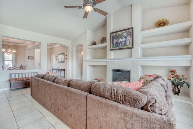 living room with ceiling fan, built in features, ornamental molding, light tile patterned floors, and arched walkways