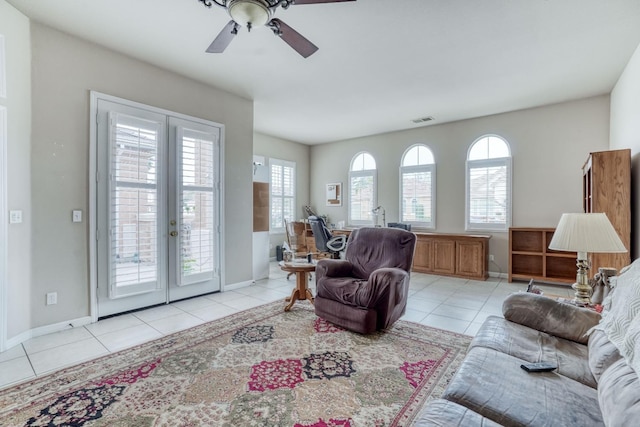 living area with light tile patterned floors, baseboards, visible vents, and ceiling fan