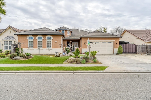 view of front of property featuring a gate, driveway, stucco siding, a garage, and a tile roof