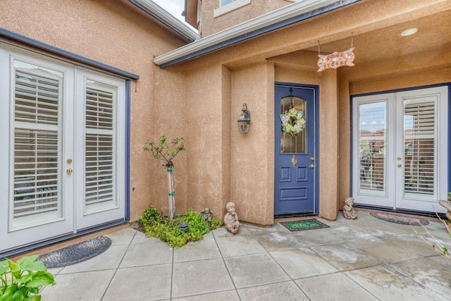 view of exterior entry with a patio, french doors, and stucco siding