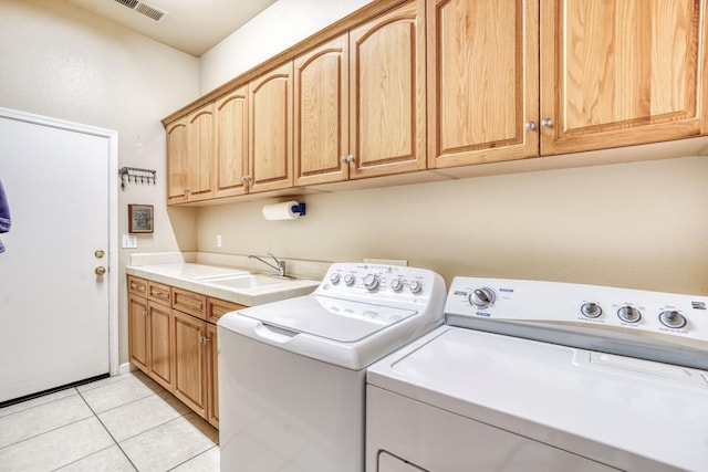 clothes washing area featuring visible vents, washer and dryer, light tile patterned flooring, cabinet space, and a sink