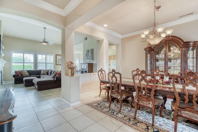 dining space with light tile patterned floors, visible vents, a premium fireplace, ornamental molding, and ceiling fan with notable chandelier