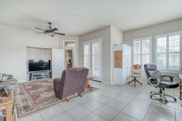 living area with light tile patterned floors, a ceiling fan, and baseboards