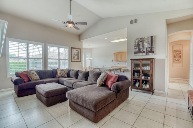 living room with visible vents, baseboards, light tile patterned floors, arched walkways, and a ceiling fan