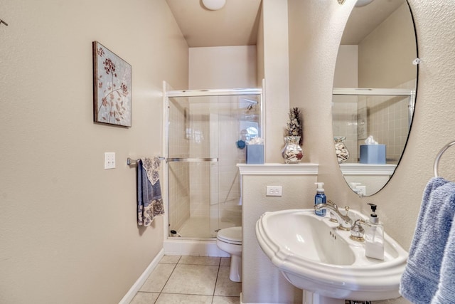 bathroom featuring tile patterned flooring, baseboards, toilet, a stall shower, and a sink