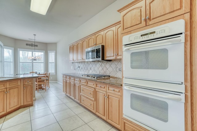 kitchen with light tile patterned floors, light brown cabinetry, decorative backsplash, stainless steel appliances, and a chandelier