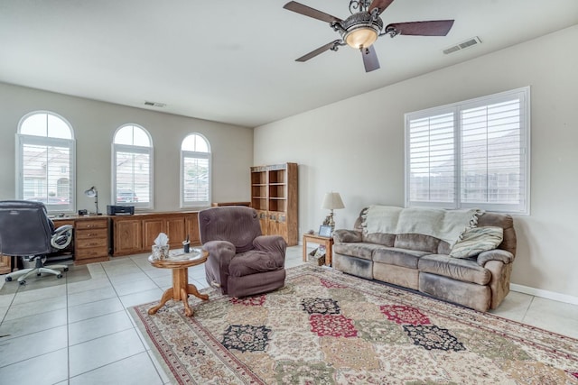 living room featuring light tile patterned floors, visible vents, and ceiling fan