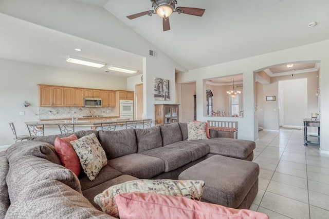 living room featuring visible vents, baseboards, ceiling fan with notable chandelier, arched walkways, and light tile patterned flooring