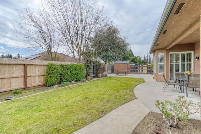 view of yard featuring a patio area, a storage unit, a fenced backyard, and an outbuilding