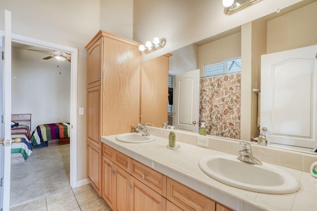 ensuite bathroom with tile patterned flooring, double vanity, a ceiling fan, and a sink