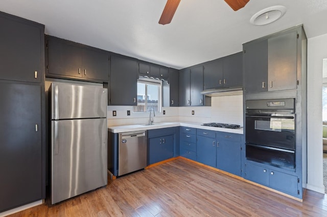 kitchen with a warming drawer, a ceiling fan, stainless steel appliances, light wood finished floors, and light countertops