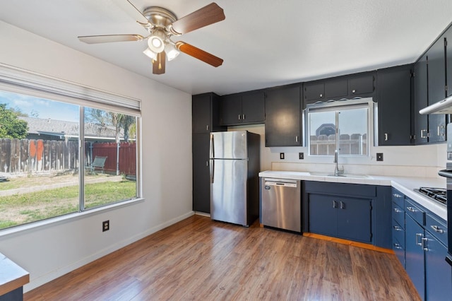 kitchen featuring baseboards, dark wood finished floors, appliances with stainless steel finishes, a ceiling fan, and a sink