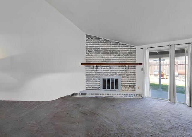 unfurnished living room with vaulted ceiling, a brick fireplace, and carpet floors