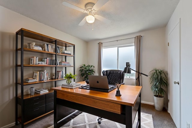 office area featuring a textured ceiling, baseboards, dark carpet, and ceiling fan