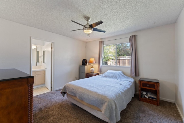 bedroom with connected bathroom, light colored carpet, baseboards, and a textured ceiling