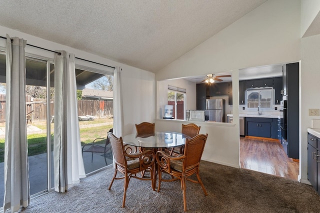 carpeted dining area featuring a textured ceiling, vaulted ceiling, a ceiling fan, and a sink