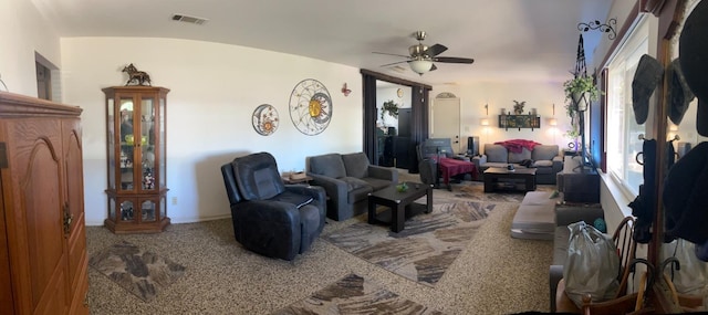 living area with a ceiling fan, visible vents, and baseboards