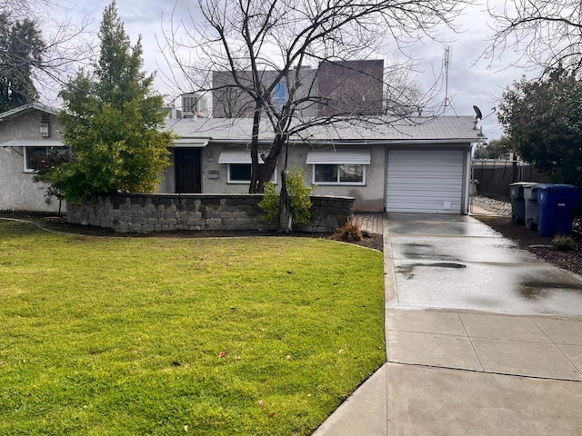 view of front of home featuring an attached garage, fence, a front yard, stucco siding, and driveway