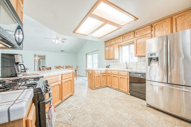 kitchen featuring ceiling fan, tile counters, lofted ceiling, a peninsula, and black appliances