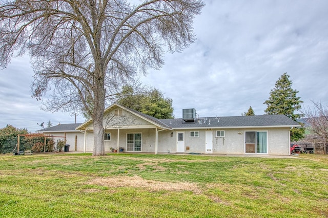 back of house featuring central air condition unit, a lawn, and stucco siding