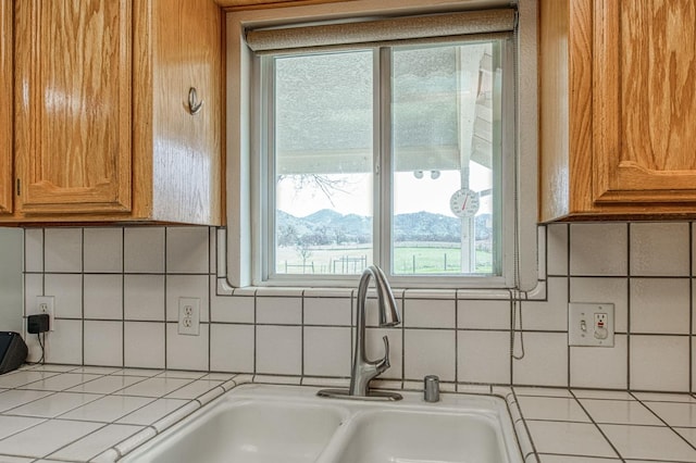 kitchen with decorative backsplash, brown cabinets, light countertops, and a sink