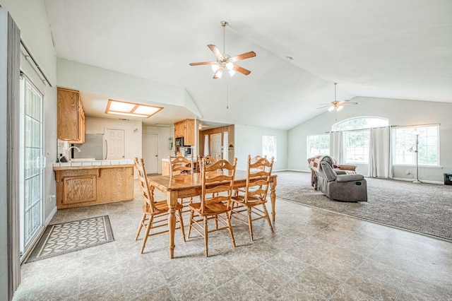 dining space featuring lofted ceiling, light carpet, baseboards, and ceiling fan