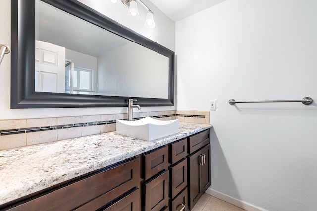 bathroom featuring tile patterned flooring, backsplash, vanity, and baseboards