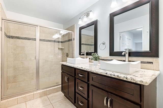 bathroom with tile patterned floors, a stall shower, double vanity, and a sink