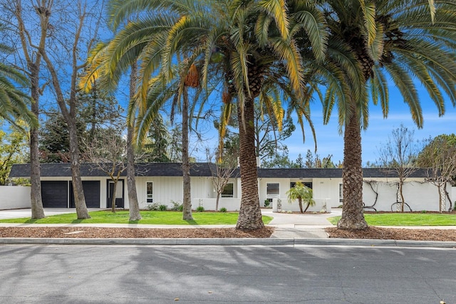 view of front of house featuring a garage, concrete driveway, and a front lawn