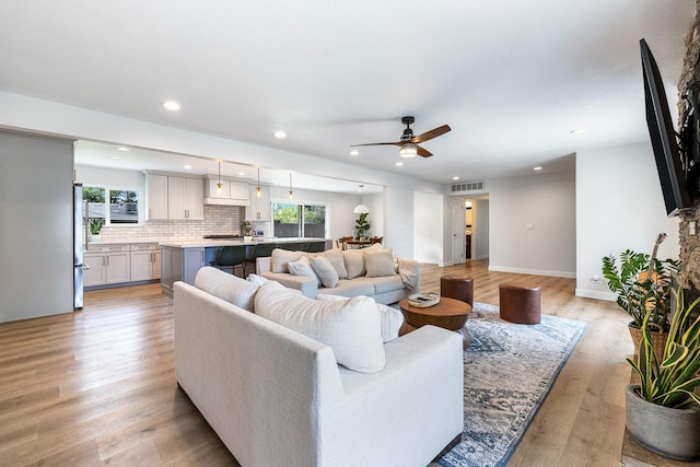 living area with a ceiling fan, visible vents, light wood finished floors, baseboards, and recessed lighting