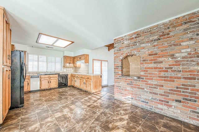 kitchen featuring brick wall, white dishwasher, freestanding refrigerator, light countertops, and backsplash