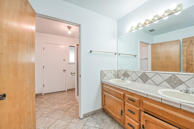 bathroom featuring double vanity, tasteful backsplash, visible vents, and a sink