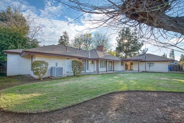 back of property featuring a yard, central AC, and a chimney