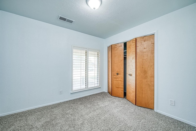 unfurnished bedroom featuring baseboards, visible vents, a closet, a textured ceiling, and carpet flooring