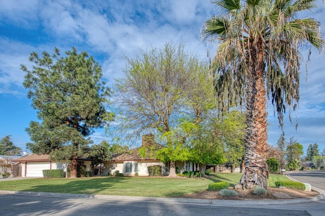 view of front facade featuring a front yard, an attached garage, and driveway